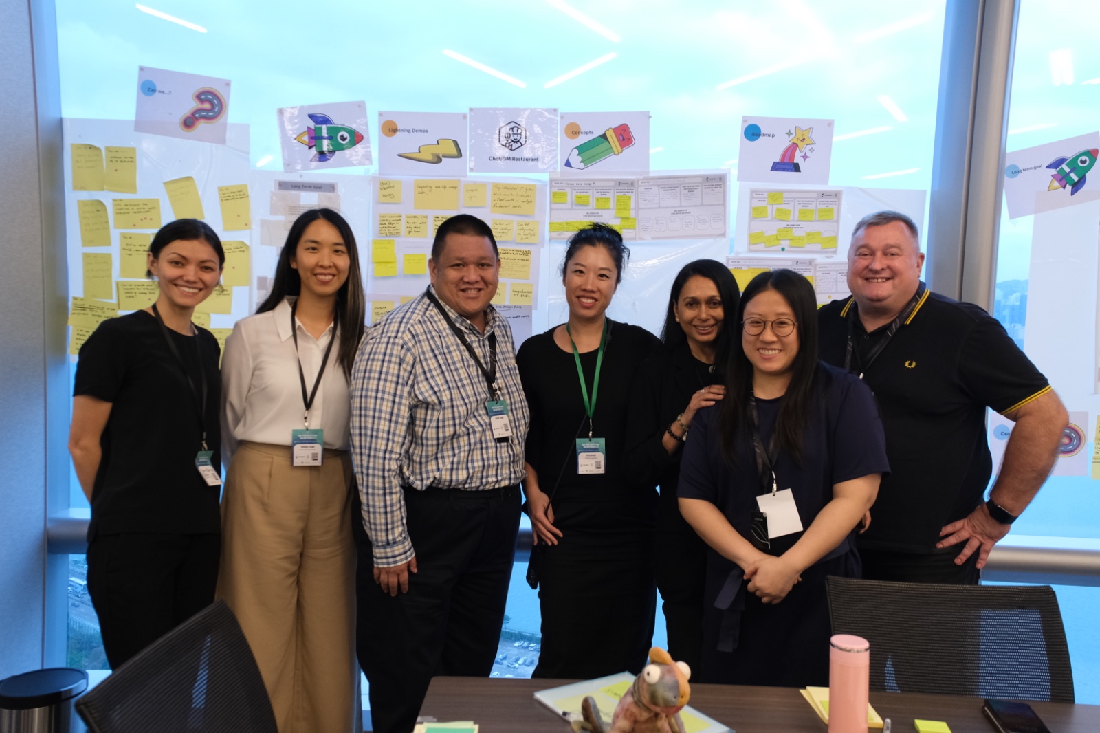 UnConference team photo — group in front of workshop wall with sticky notes and visual outputs
