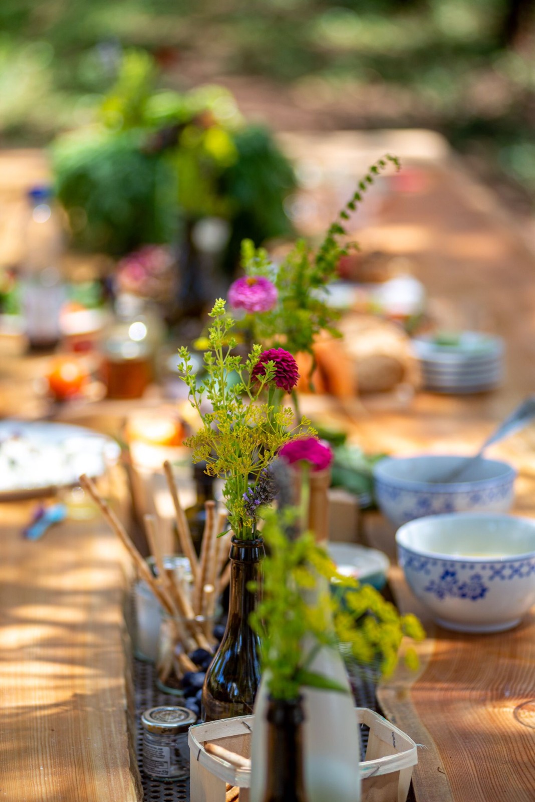 Outdoor communal table set with wildflowers and seasonal food