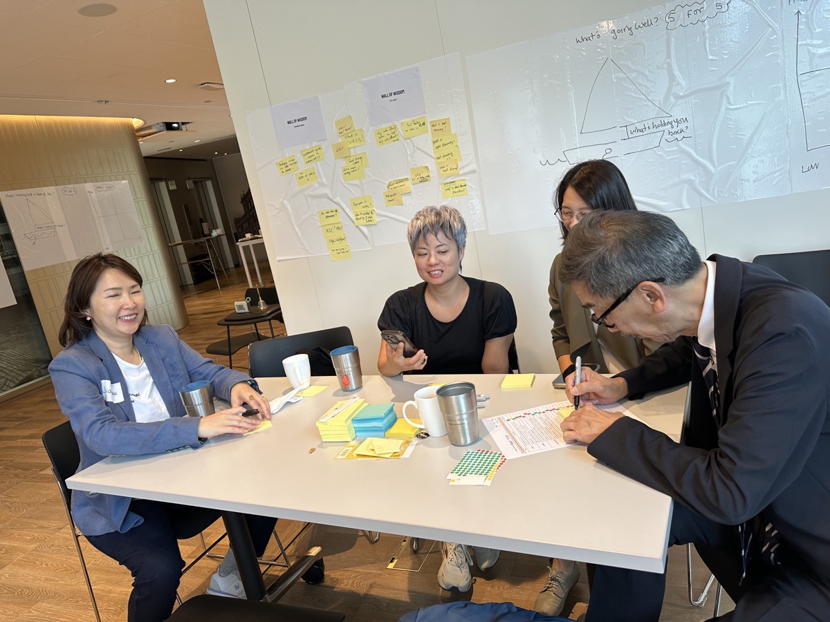 Four professionals engaged around table with sticky notes at workshop